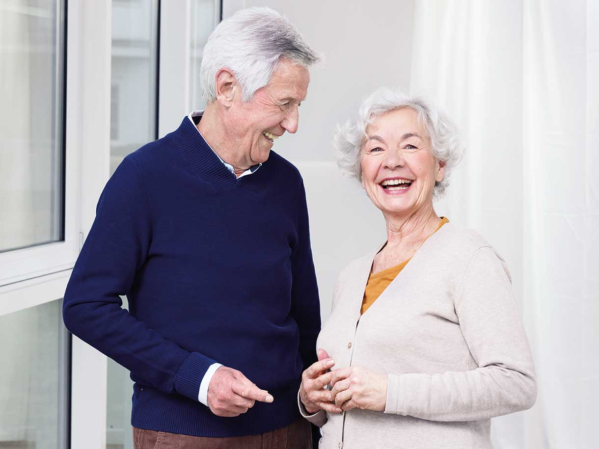 An older man and older woman standing together smiling