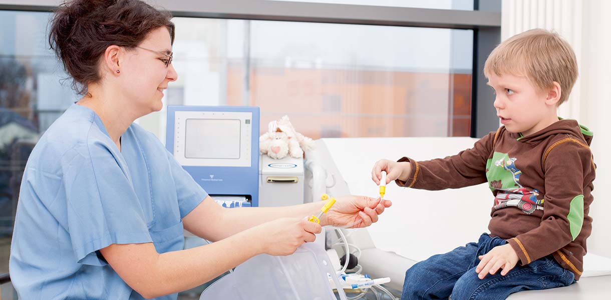 Pflegekraft und Junge vor einer Dialysemaschine